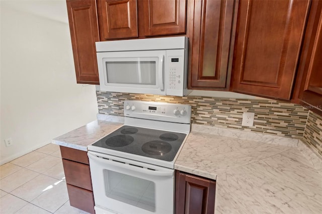 kitchen with light tile patterned floors, white appliances, tasteful backsplash, and light stone counters