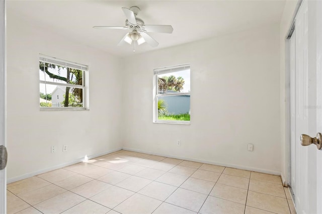 tiled spare room featuring plenty of natural light and ceiling fan