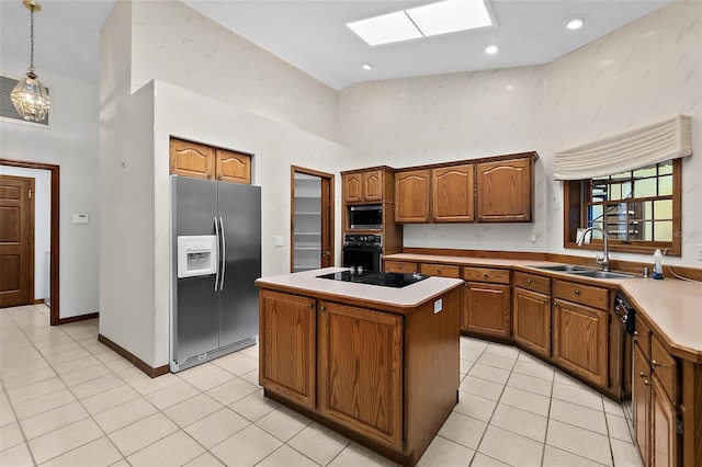 kitchen with pendant lighting, a skylight, sink, a center island, and black appliances