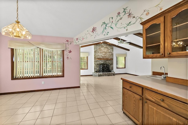 kitchen featuring ceiling fan, a fireplace, light tile patterned flooring, decorative light fixtures, and vaulted ceiling