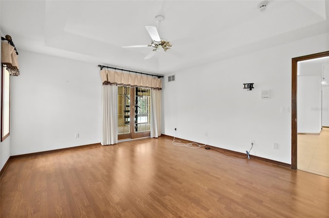 unfurnished room with a tray ceiling, wood-type flooring, and ceiling fan