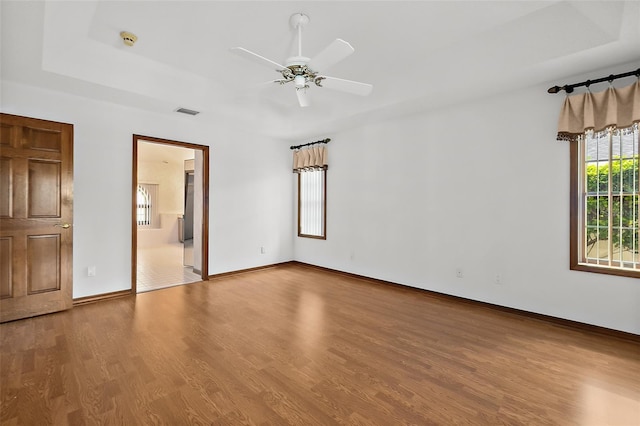 spare room featuring hardwood / wood-style flooring, ceiling fan, and a tray ceiling