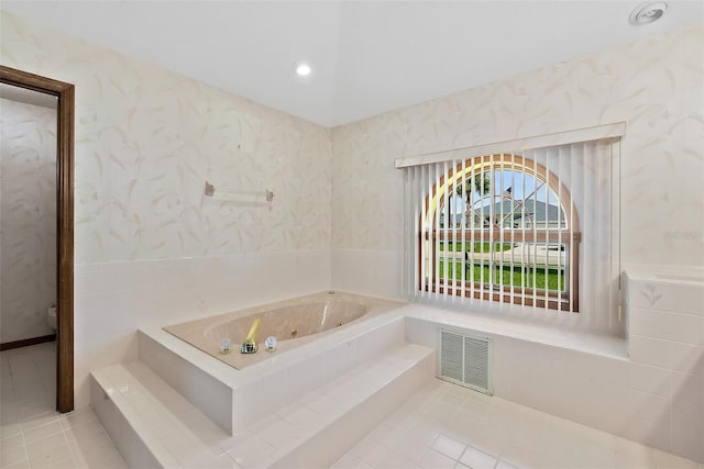 bathroom with a relaxing tiled tub and tile patterned flooring