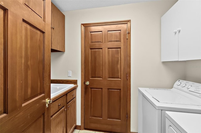 clothes washing area with cabinets, sink, and washer and clothes dryer