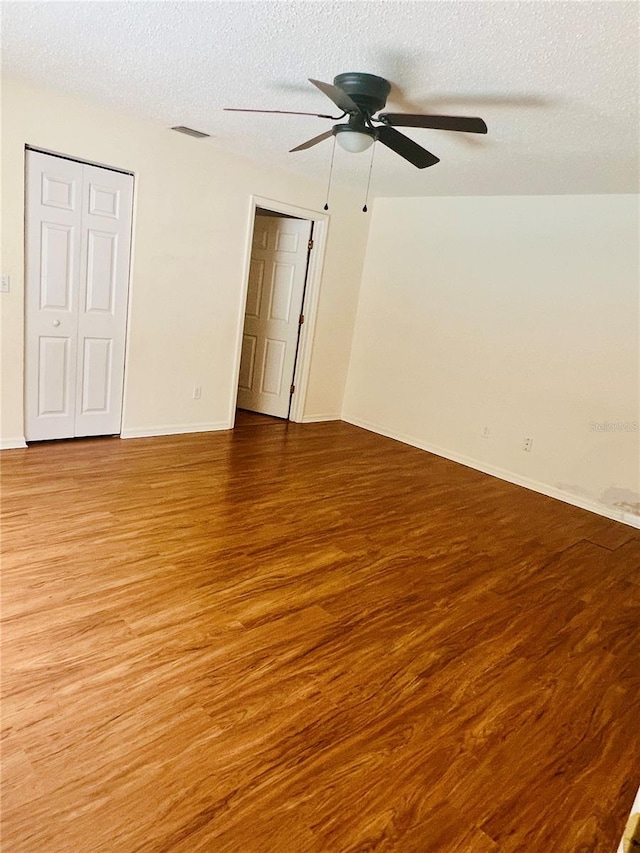 spare room featuring a textured ceiling, wood-type flooring, and ceiling fan