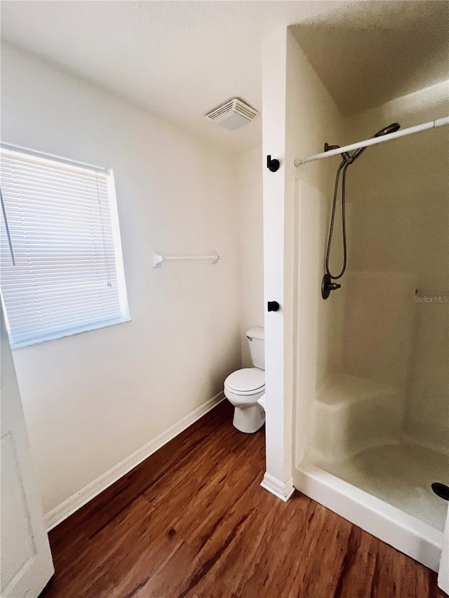 bathroom featuring a shower, wood-type flooring, and toilet