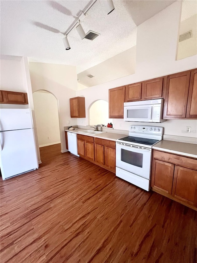 kitchen with rail lighting, a textured ceiling, dark hardwood / wood-style flooring, and white appliances