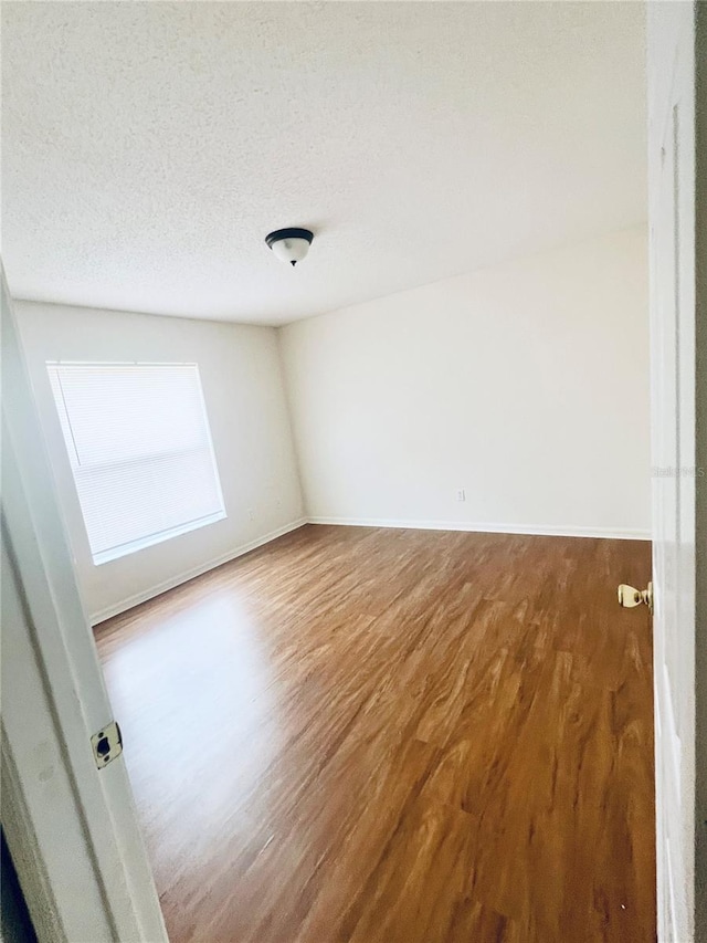 empty room featuring a textured ceiling and hardwood / wood-style flooring