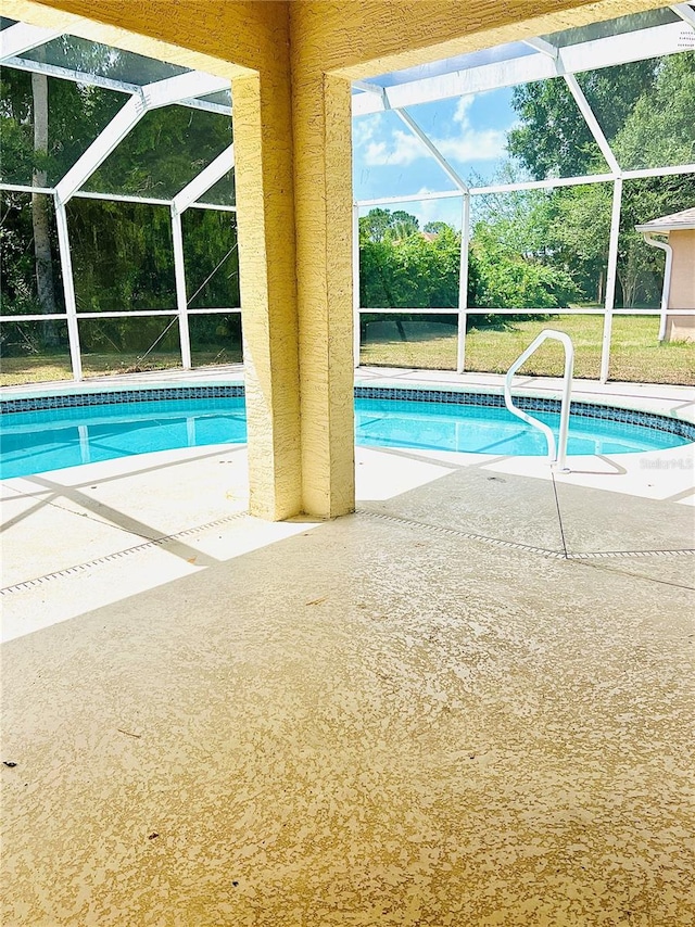 view of pool featuring glass enclosure and a patio area