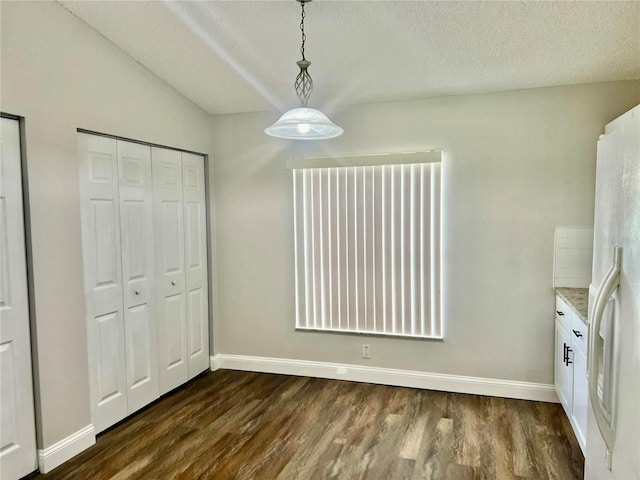 unfurnished dining area with dark wood-type flooring and a textured ceiling