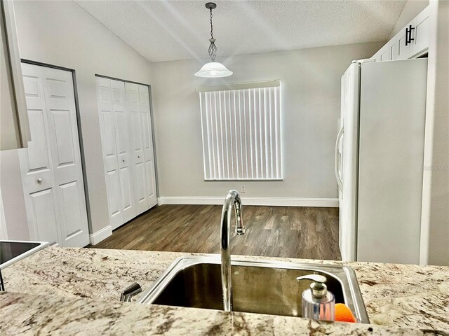 kitchen featuring dark wood-type flooring, sink, white refrigerator, pendant lighting, and white cabinets