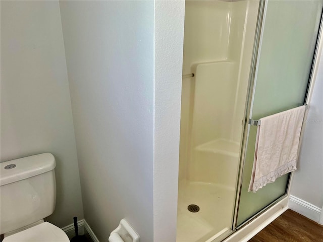 bathroom featuring walk in shower, toilet, and hardwood / wood-style floors