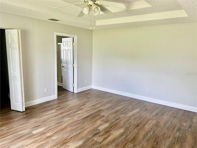 spare room with hardwood / wood-style flooring, a raised ceiling, and a textured ceiling