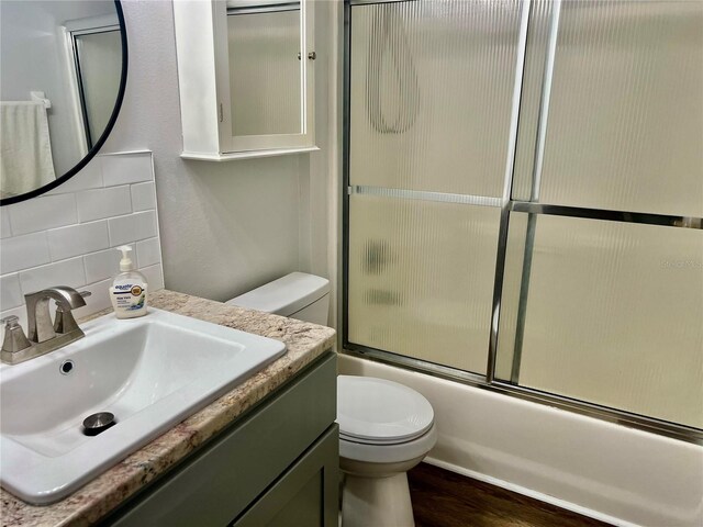 full bathroom with toilet, tasteful backsplash, vanity, hardwood / wood-style flooring, and enclosed tub / shower combo