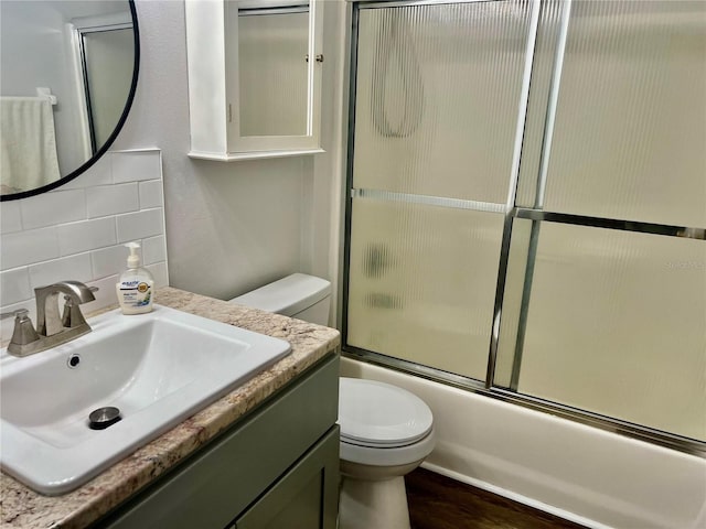 full bathroom featuring enclosed tub / shower combo, vanity, wood-type flooring, decorative backsplash, and toilet