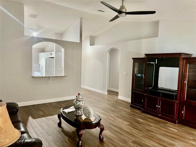 living room with hardwood / wood-style floors, ceiling fan, a textured ceiling, and vaulted ceiling