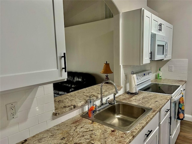 kitchen with sink, white appliances, white cabinetry, backsplash, and light stone counters