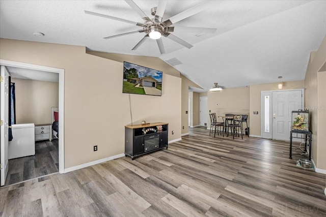 living room with ceiling fan, vaulted ceiling, a textured ceiling, and hardwood / wood-style floors