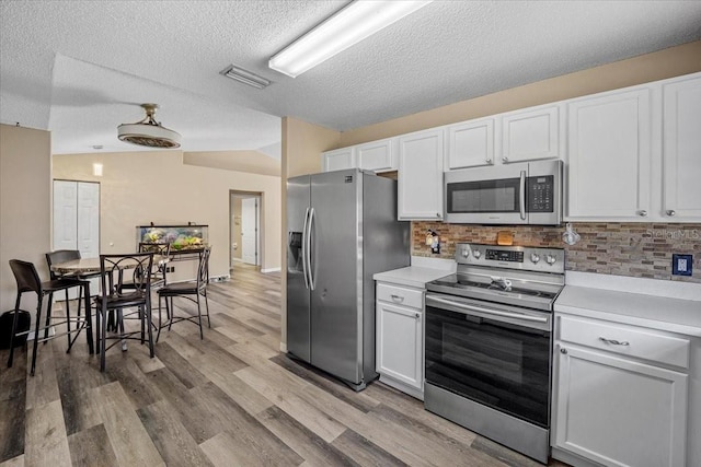 kitchen featuring white cabinetry, backsplash, appliances with stainless steel finishes, and light wood-type flooring