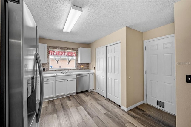 kitchen with light hardwood / wood-style floors, white cabinetry, stainless steel appliances, and tasteful backsplash