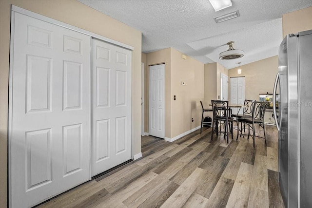 dining room featuring vaulted ceiling, a textured ceiling, and hardwood / wood-style floors