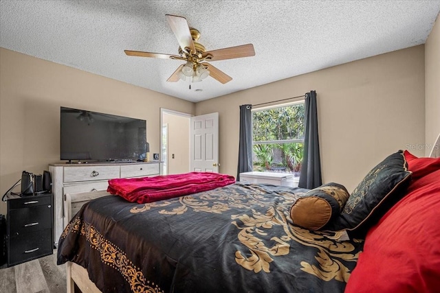 bedroom with ceiling fan, light hardwood / wood-style floors, and a textured ceiling