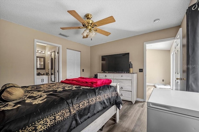 bedroom with ensuite bathroom, ceiling fan, wood-type flooring, and a textured ceiling