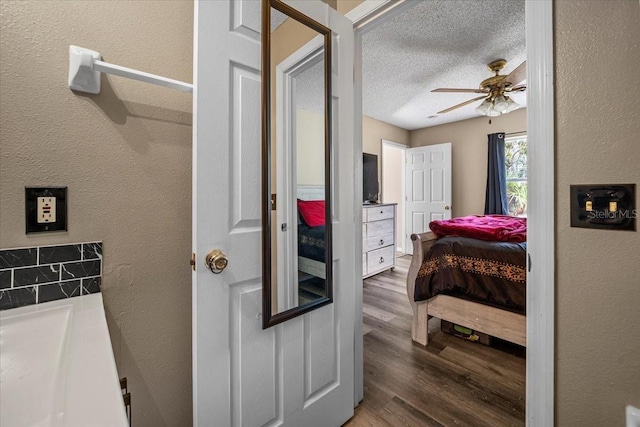 bathroom with hardwood / wood-style floors, ceiling fan, and a textured ceiling