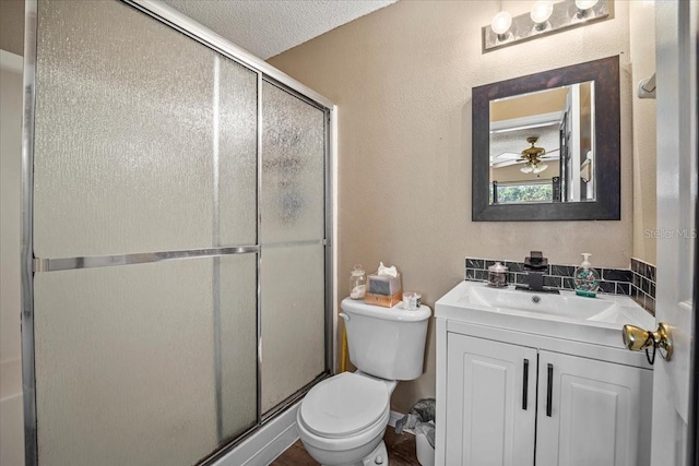 bathroom featuring toilet, a textured ceiling, an enclosed shower, and vanity