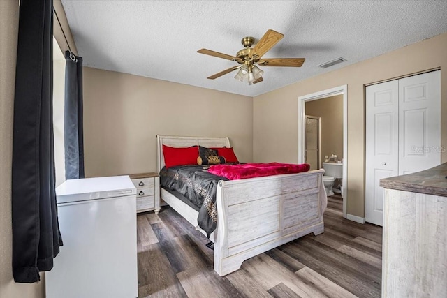 bedroom with ceiling fan, dark hardwood / wood-style floors, a textured ceiling, and ensuite bath