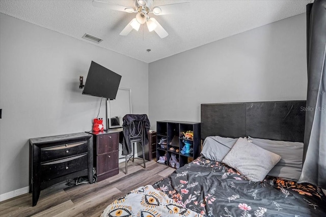 bedroom featuring ceiling fan, light hardwood / wood-style floors, and a textured ceiling