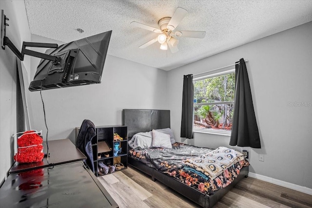 bedroom with a textured ceiling, ceiling fan, and light hardwood / wood-style floors