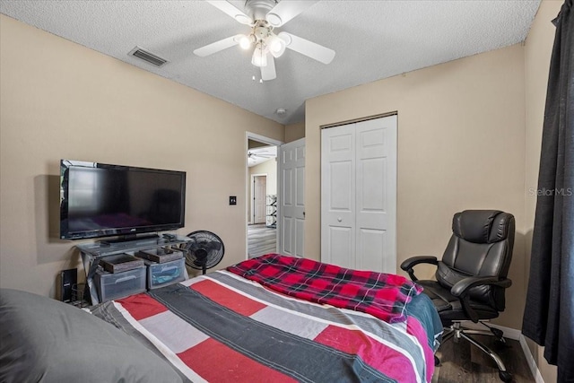 bedroom featuring ceiling fan, wood-type flooring, a textured ceiling, and a closet