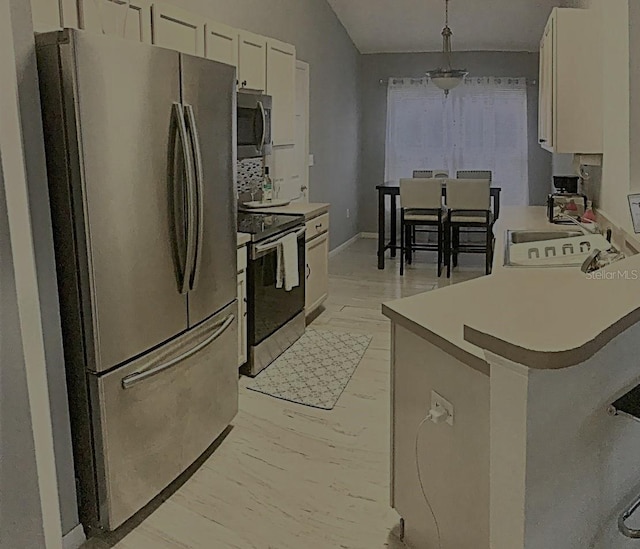 kitchen featuring sink, light wood-type flooring, appliances with stainless steel finishes, pendant lighting, and white cabinets