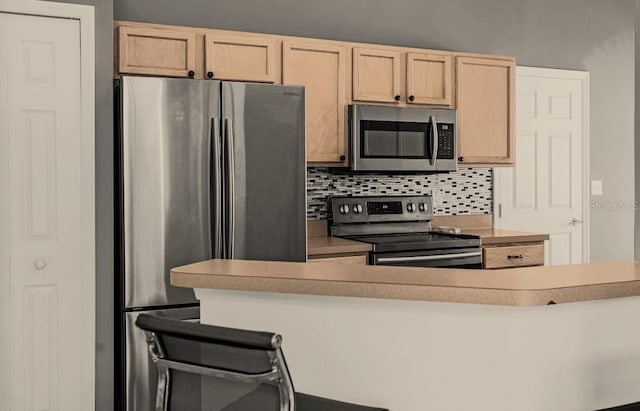 kitchen featuring backsplash, light brown cabinets, a breakfast bar, and appliances with stainless steel finishes