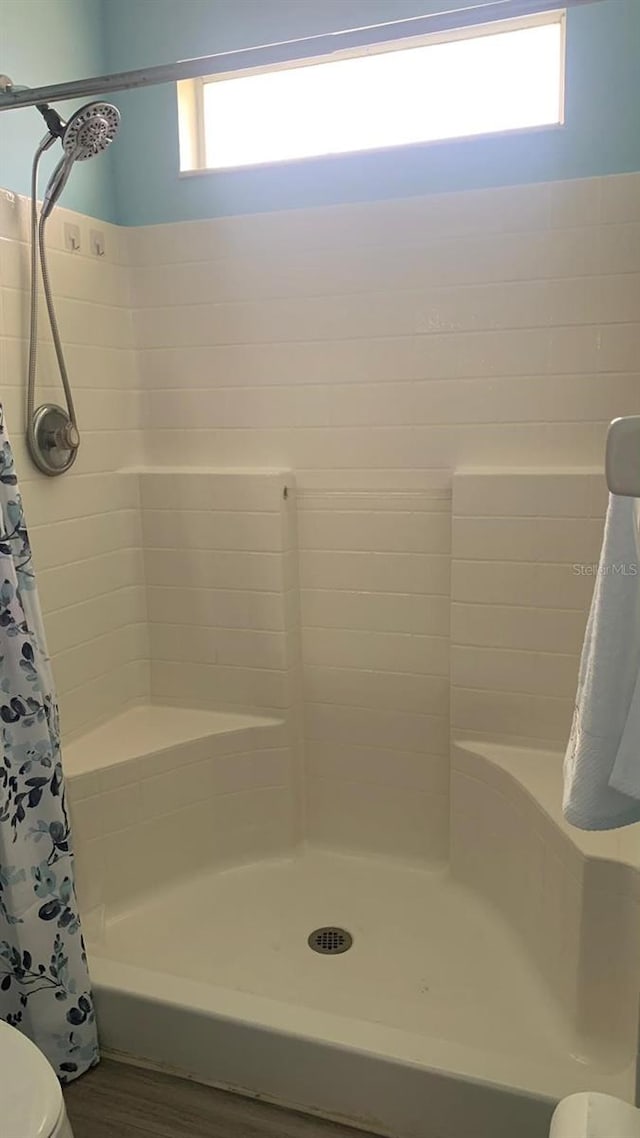 bathroom featuring wood-type flooring, plenty of natural light, toilet, and a shower with shower curtain