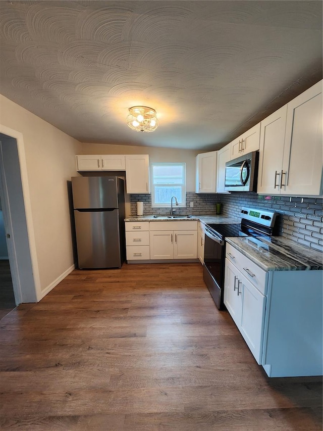 kitchen with hardwood / wood-style floors, white cabinetry, sink, and stainless steel appliances