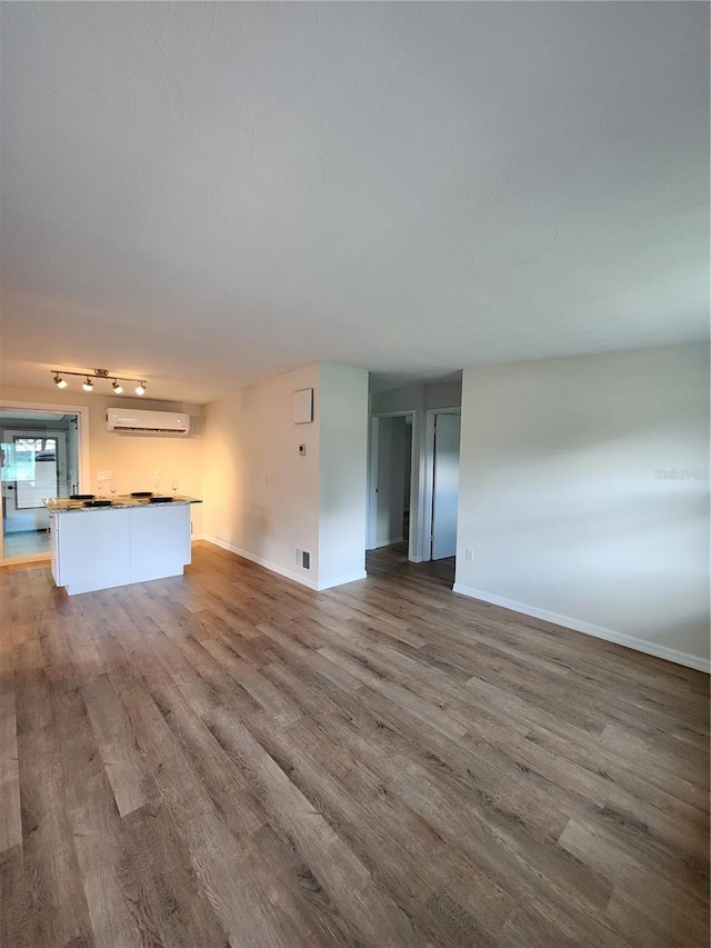 unfurnished living room featuring hardwood / wood-style flooring and a wall mounted air conditioner