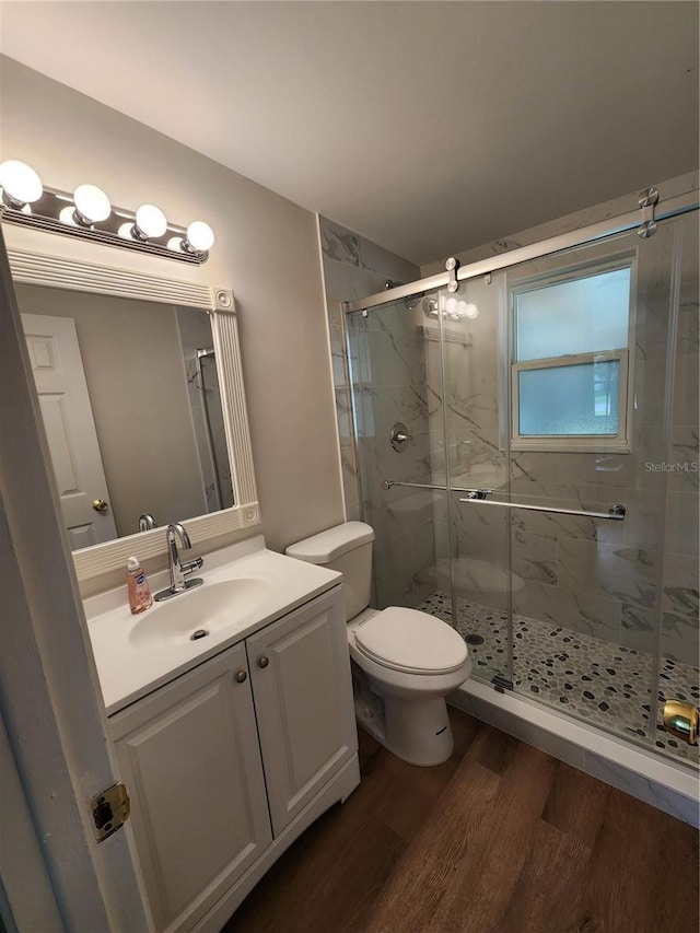 bathroom featuring toilet, vanity, an enclosed shower, and hardwood / wood-style flooring