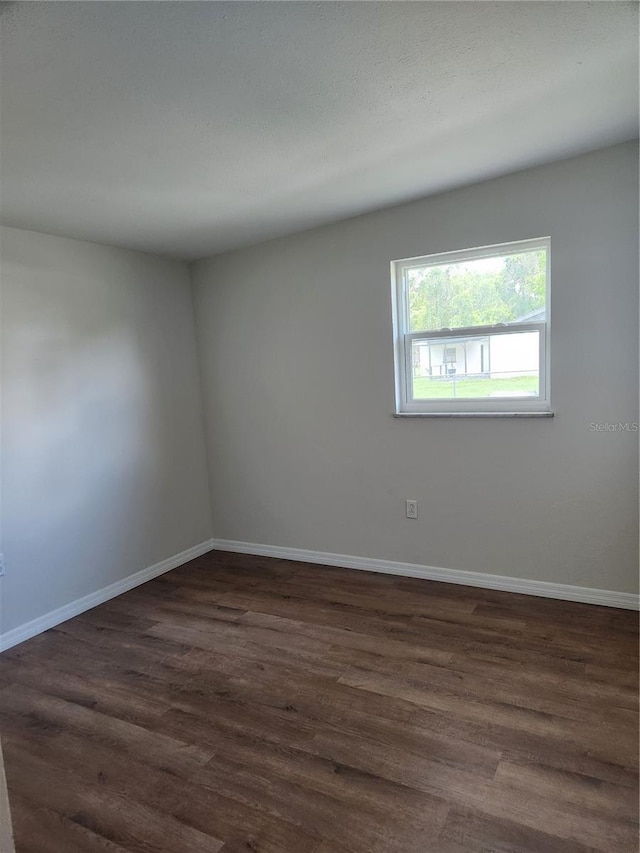 unfurnished room with dark wood-type flooring