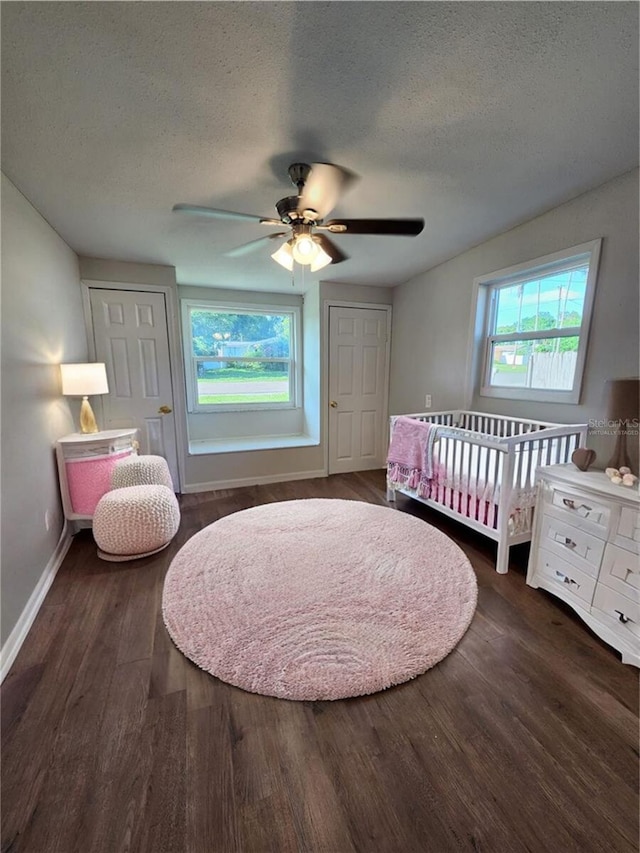 bedroom featuring multiple windows, a textured ceiling, dark hardwood / wood-style floors, and ceiling fan