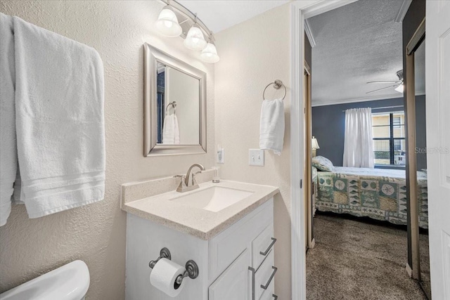 bathroom featuring vanity, ceiling fan, toilet, ornamental molding, and a textured ceiling