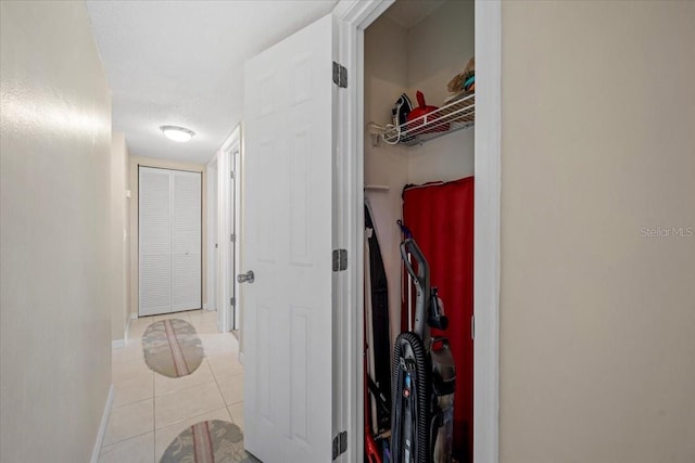 hall featuring light tile patterned floors and a textured ceiling