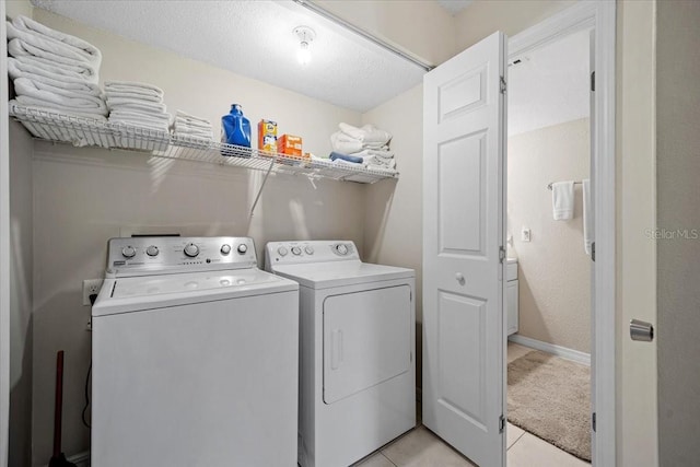 laundry room featuring washer and clothes dryer, light tile patterned flooring, and a textured ceiling