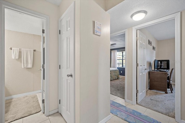 hall featuring light carpet and a textured ceiling