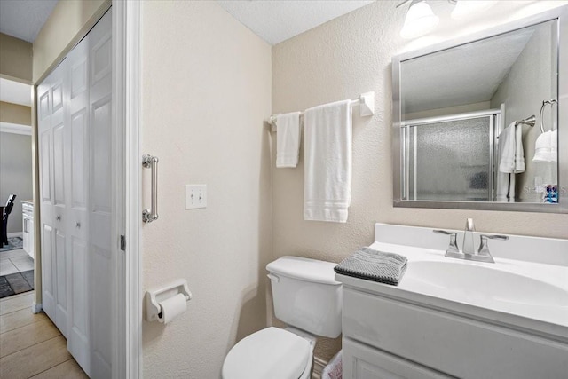 bathroom with tile patterned floors, vanity, toilet, and a shower with shower door