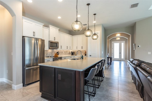 kitchen featuring appliances with stainless steel finishes, a kitchen breakfast bar, sink, a center island with sink, and white cabinetry