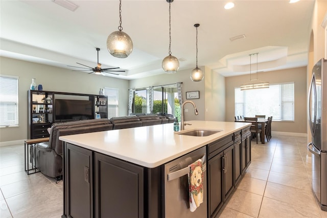 kitchen featuring appliances with stainless steel finishes, a center island with sink, a raised ceiling, and sink