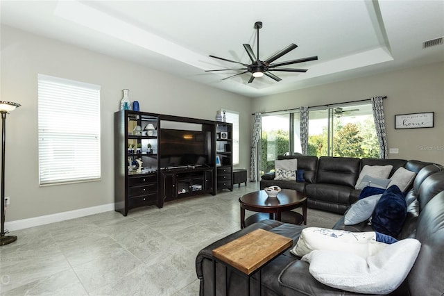 living room with a tray ceiling and ceiling fan