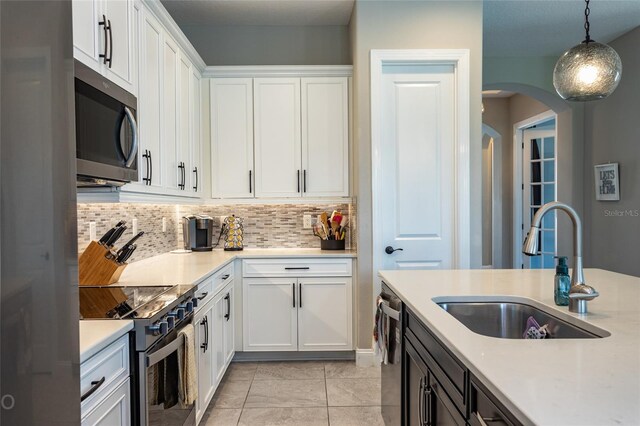 kitchen featuring decorative light fixtures, white cabinetry, sink, and appliances with stainless steel finishes